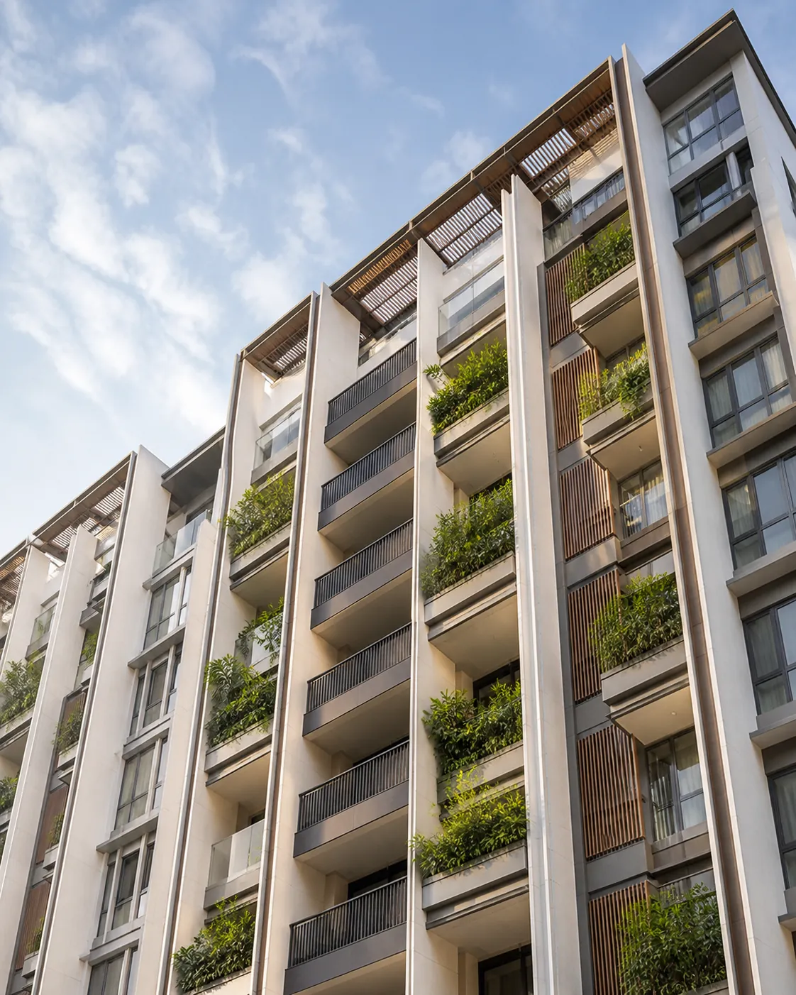 The facade of a newly completed condominium tower with deep planted balconies against a tropical sky.