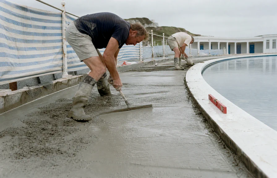 Workers floating new concrete along the curved edge of the deck.